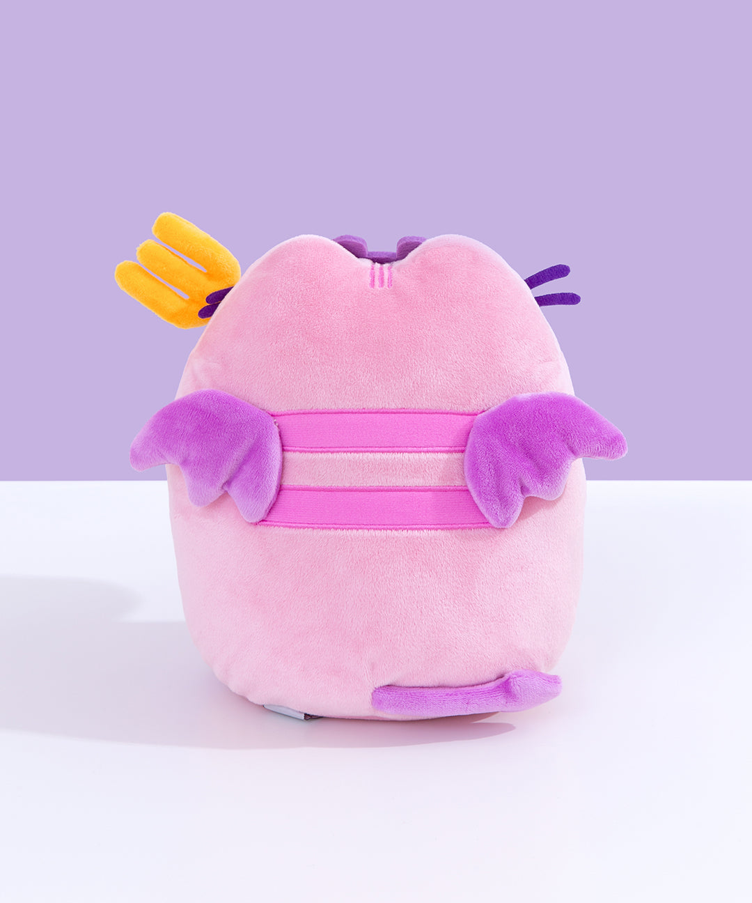 Back view of Devil’s Food Cake Pusheen Plush. This view shows Pusheen’s pink back stripes, purple wings, and purple forked tail.  