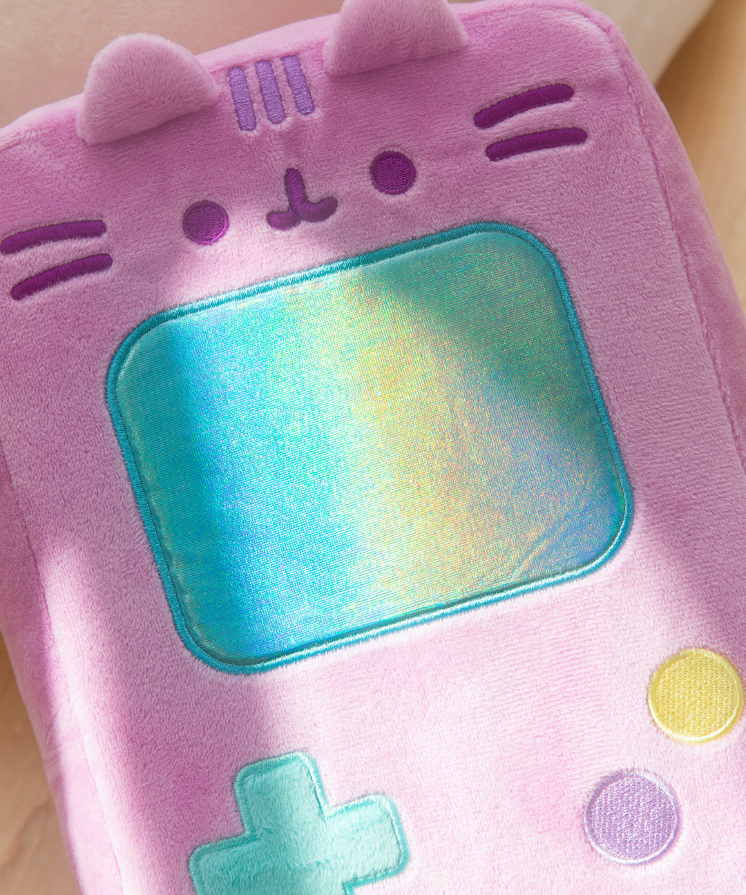 Sunlight shines on the blue rectangular screen of the retro handheld console plush. 