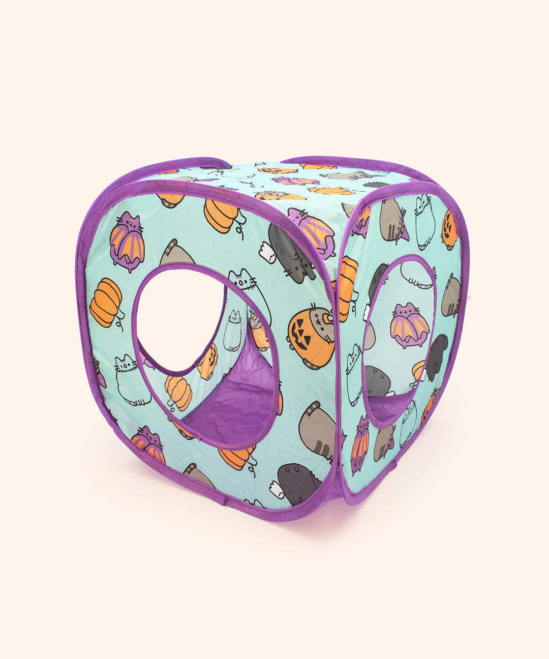Full view of the Pusheen Pet Halloween Collapsible Box. The square cube has a rounded opening in three sides of the box. The green and purple pet toy has all over pattern of Pusheen halloween-themed icons.