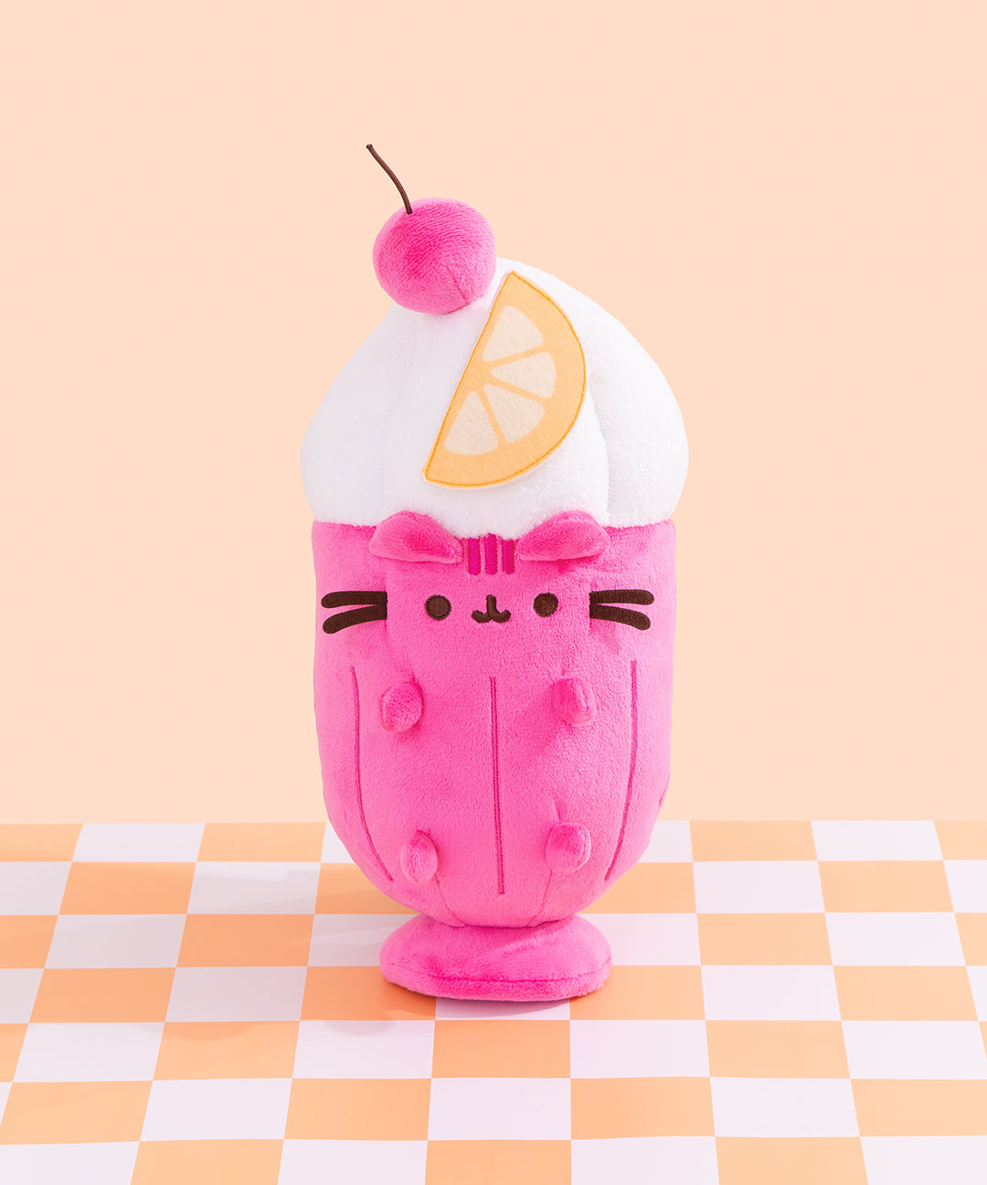 Front view of the Pusheen Fruits Fruit Parfait Plush. Pusheen the Cat takes the form of a delightful dessert served with a whipped topping, hot pink cherry, and orange slice. The whipped topping is white and extends off the glass-shaped body. 