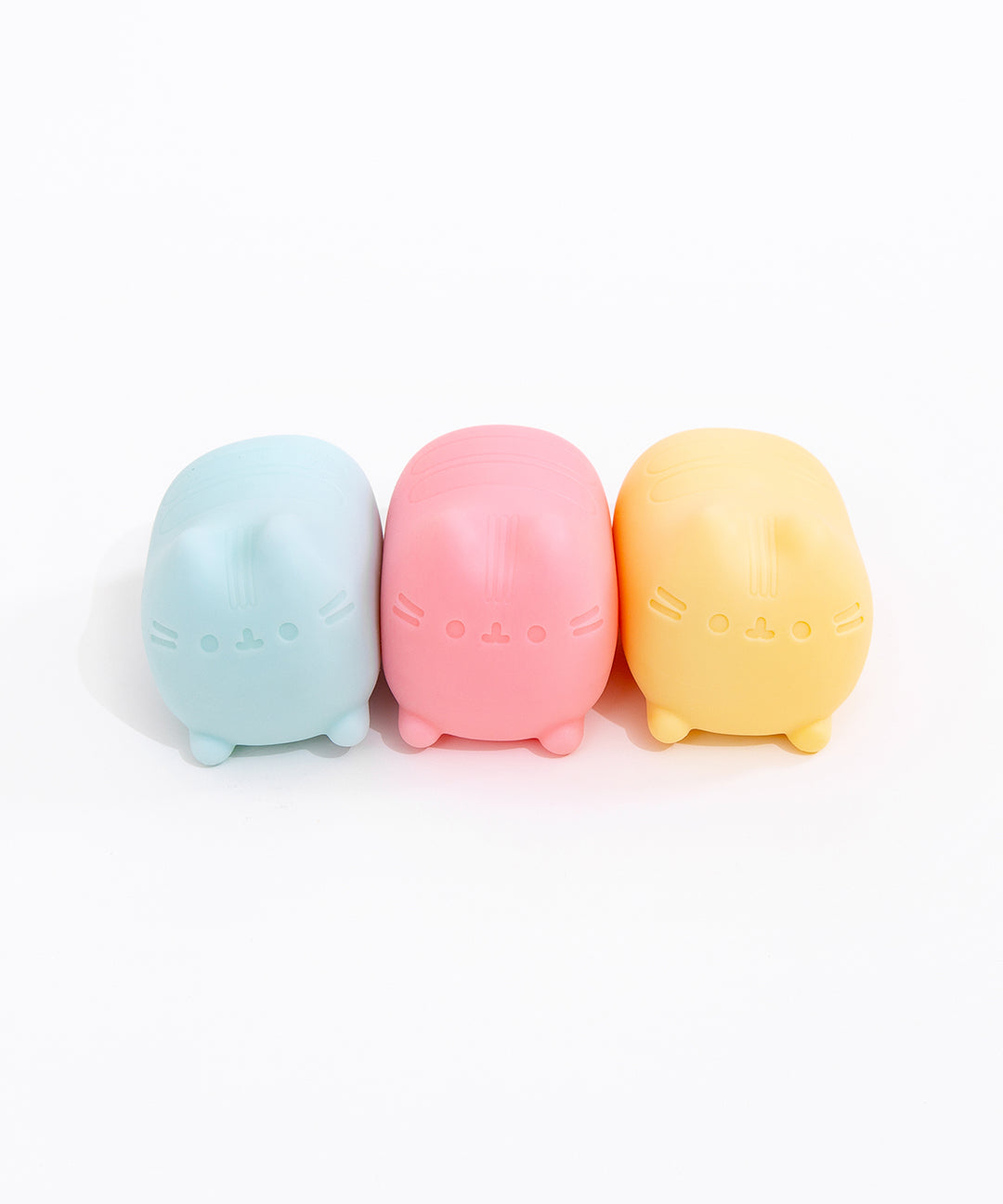 Pusheen Surprise Squishu Assortment of toys. From left to right are blue, pink, and yellow variations of gel-filled toys that resemble Pusheen the Cat.