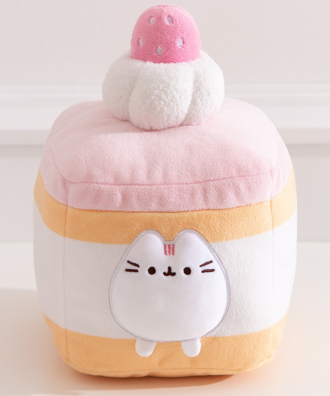 Close-up of the Pusheen figure within the plush cake and cream layers. Pusheen the Cat's two front paws sit outside of the cream layer.