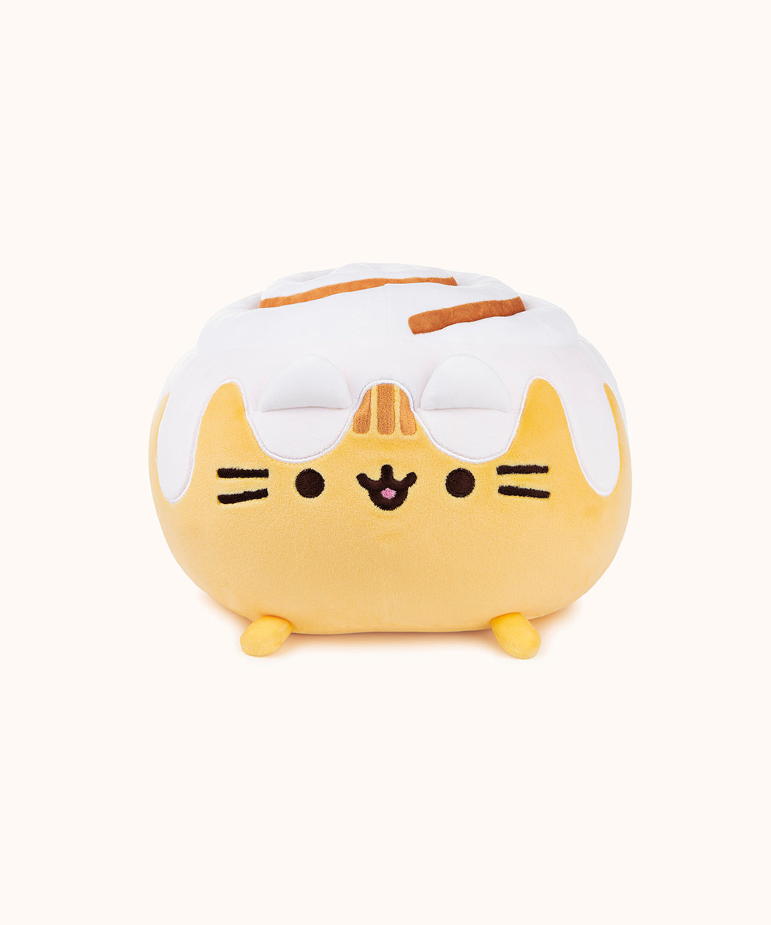 Front view of the Cinnamon Roll Squisheen in front of a white background. Pusheen's frosting covered ears blends in visually with the rest of the frosting on top of her.