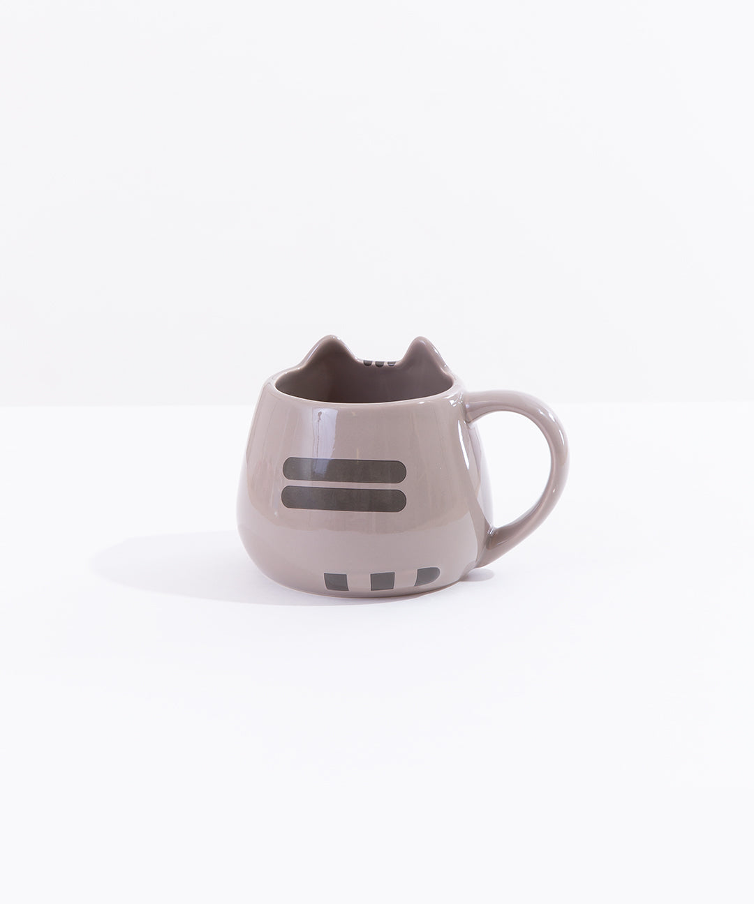 The back of the Pusheen Character Mug in front of a white background. On the back of the mug there are two dark grey back stripes printed in the middle of the mug’s back. At the bottom there is a trio of small dark grey squares, creating the illusion of Pusheen’s tail pointing to the right. The rim of the mug at the back is smooth and round.